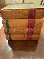 Side view of four leather-bound antique books, showing spine labels in red and black with gold embossed text indicating 'Littell's Living Age'