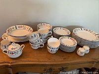 Complete set of dishes displayed including plates, bowls, cups, saucers, salt and pepper shakers, creamer, sugar bowl, and serving dishes all with matching floral pattern.