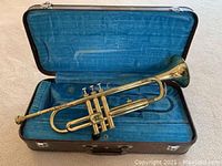 Open case showing trumpet laid across blue velvet interior