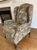 Winged back recliner chair showing side angle with upholstery pattern and wooden legs