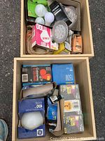 Photo shows lot of assorted light bulbs in two wooden boxes, including multiple bulbs in original packaging and loose bulbs of varying sizes and wattages.