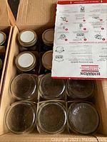 Close-up view of some jars without lids and a Behradin instruction sheet on usage and sealing of Mason jars.