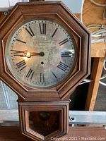 Front view of octagonal wooden bezel and metal Roman numeral dial