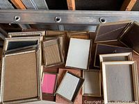 Assorted picture frames grouped on a wooden surface, showing different sizes, styles, and finishes.
