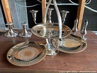 Photo showing all silver items including two candle holders, two-tier tray, salt and pepper shakers, and small candle holders with visible tarnish.