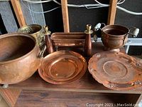 View of multiple copper items including pots, candlesticks, trays, and urn-style container.