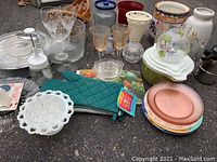 Wide view of assorted kitchen and decor items including serving dishes, glassware, oven mitt, and decorative pieces.