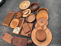 Top view of all handcrafted wooden serving dishes and boards showing variety of plates, bowls, trays, and cutting boards with natural wood and painted details.