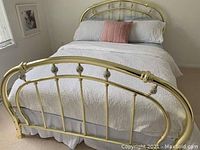 Queen brass headboard with spindle details and finial accents shown attached to a queen bed.