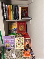 Books displayed on shelving and countertop showing varied titles including children's books, novels, and instructional books.