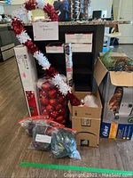 Overview of assorted Christmas decorations including garlands, ornament balls, boxes, and a shelving unit.