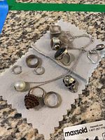 Nine jewelry pieces displayed on white cloth over granite surface.