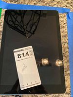 Front view of iPad showing screen with physical home button and a MaxSold sticker