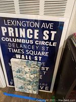 Another image of the New York themed street sign showing the text details and part of another decorative item in front.