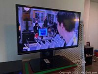 Samsung 32 inch TV on stand showing a scene from a TV show, confirms screen size and brand