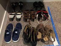 Six pairs of women's size 7 shoes on carpeted floor, including sneakers, pumps and sandals in various colors and styles