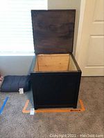 Open view of handmade wooden chest showing interior natural wood finish and black exterior.