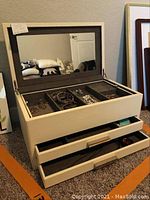 Open jewelry box showing compartments with costume jewelry inside