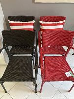 Front view of one black and one red chair with striped pillows against wall