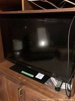 Front angle view of Samsung TV on wooden cabinet showing screen and remote