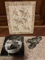 Photo showing two soapstone art pieces: a rectangular relief panel of carved birds and an abstract figurine.