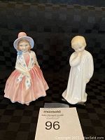 Two Royal Doulton figurines, Lily and Darling, on black checkered background