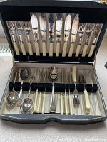 Open black case showing 6 fish forks, 6 soup spoons and 6 serving spoons with ivory handles arranged inside.