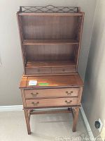 Front view showing two open shelves above two small pull-out drawers above drop-front writing surface