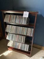 Front view of dark wood four-shelf CD holder loaded with CDs
