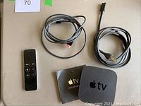 Top down photo showing Apple TV, remote, HDMI cable, power cord and setup booklet
