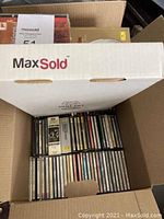 Box with compact discs stacked vertically and some loose discs on top