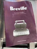 Purple instruction booklet titled 'Breville the Smart Waffle' with image of the waffle maker on the cover.