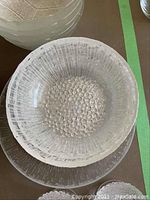 One radial textured round bowl atop matching luncheon plates, showing hobnail center and radial line pattern