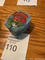 Image showing the top and side of the keepsake dish with red hibiscus flower on pale blue background