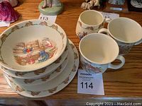 Top view of stacked Bunnykins cereal bowl, two flat bottom bowls, and three Bunnykins cups, all decorated with Bunnykins illustrations and borders