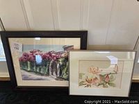 Two framed watercolor paintings seen together, one with floral magnolias and one with a Mexico scene of pink flowering trees.