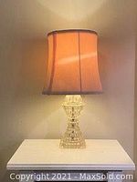 Full view of bedroom lamp illuminated to show shade and glass base details.