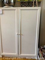 White IKEA Billy bookcase with two closed Oxberg white panel cabinet doors and white round knobs.