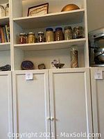 Tall white IKEA Billy bookcase with Oxberg doors viewed frontally showing open shelves with jars and bowls and closed lower cabinetry.
