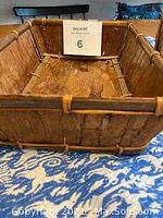 Straight-on view of rectangular basket showing interior with wood and bark construction, alongside measuring card.