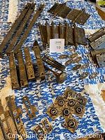 Assorted brass door hardware spread on cloth showing variety of components including faceplates, hinges, escutcheons and knob