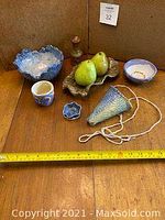 All ceramic pieces displayed on wooden surface including a scalloped blue bowl, cup, small flower dish, cone planter, tray with ceramic pears, small glaze rim bowl, and vase.