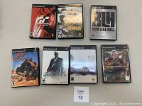 Photo showing 7 PlayStation 2 game cases arranged in 2 rows. Titles visible: Gran Turismo 3 A-Spec, The Getaway, Run Like Hell, ATV Off Road Fury, Hitman 2, Extermination, Seek and Destroy.
