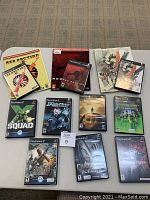 Photo showing all 10 PlayStation 2 game cases and 3 official strategy guides laid out on carpet, clearly displaying titles including Red Faction, Metal Gear Solid 2, X Squad, PSI Ops, Syphon Filter, Medal of Honor Rising Son, Champions of Norrath, and Vampire Night.