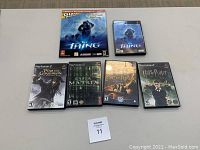 Photo showing 5 PlayStation 2 games in cases plus The Thing Official Strategy Guide book, all items arranged on a table.