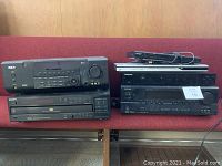 Full view of all audio/visual devices showing front panels and controls arranged on a red couch.