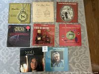 Eight vintage record albums laid out on floor with visible cover artwork and titles. Includes Don Norman, Joan Baez Noel, multiple music box and Christmas-themed albums.