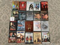 Photo of assorted DVD lot laid out in rows on carpeted floor showing front covers of titles.