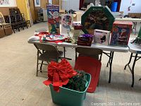 Wide view of table with all Christmas decorations and boxed items including lamp post and snowman