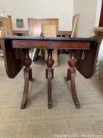 Side view showing the folded down sides and wooden pedestal legs with bases.